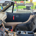 Car interior with a view of a grassy area and outdoor furniture through the windshield.