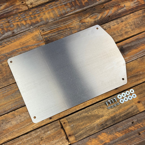A brushed metal panel with rounded corners and pre-drilled mounting holes, shown on a rustic wooden plank surface with a small set of mounting screws and washers beside it.