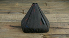 A dark gray textured car gear shift boot cover with small red and blue embroidered accents, resting on a rustic wooden plank surface.