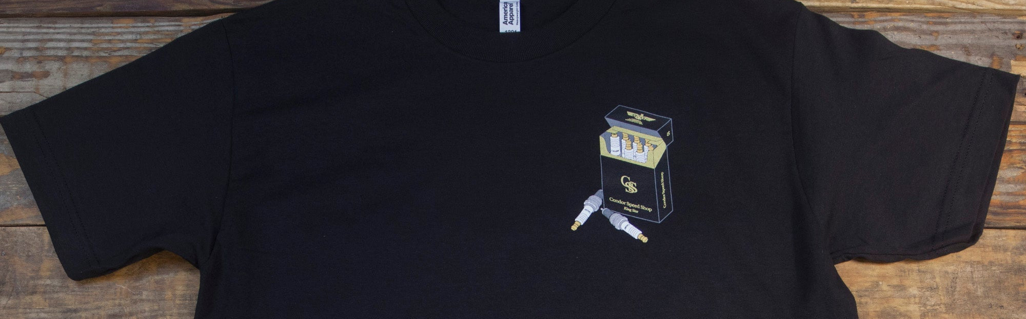 Black t-shirt with a small graphic on a wooden surface