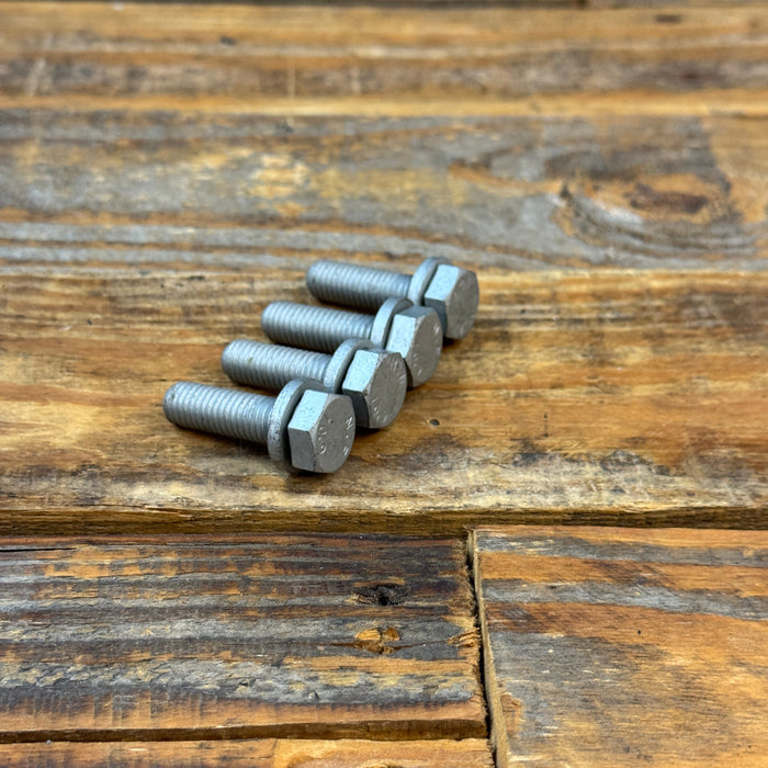 Four silver metal hex bolts with threaded shanks resting on a rustic wooden plank surface.