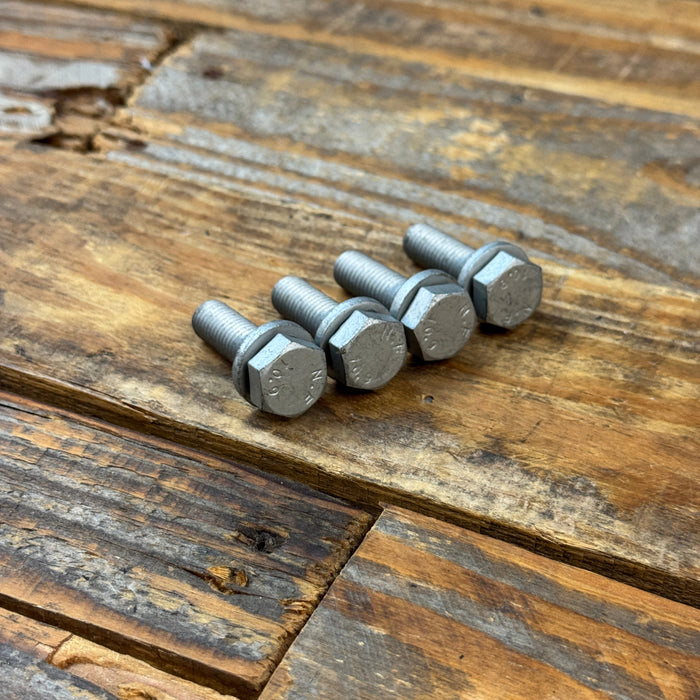Four silver hex head bolts arranged in a row on a rustic wooden plank surface.